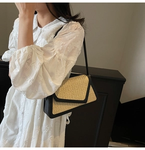 Detail of woven straw shoulder bag with black leather trim and geometric flap design