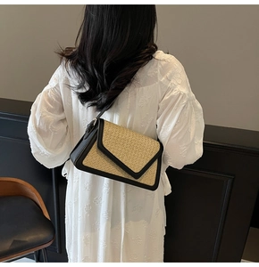 Detail view of rainbow straw woven shoulder bag with black leather trim on white dress