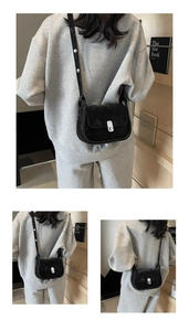 Detail of black leather crossbody bag with silver buckle and adjustable shoulder strap