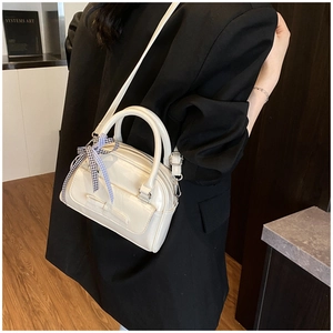 Sac beige chic avec nœud et ruban à carreaux porté par un mannequin en blazer