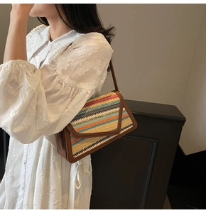 Detailed macro view of a colorful rainbow straw woven flap bag with brown leather trim