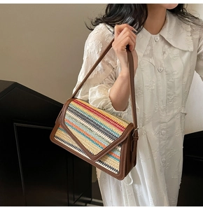 Detail of rainbow straw woven shoulder bag with brown leather trim and V-shaped flap