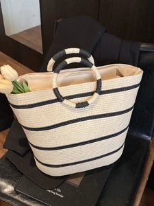 Summer straw tote bag with black and white stripes and round handles for beach vacation
