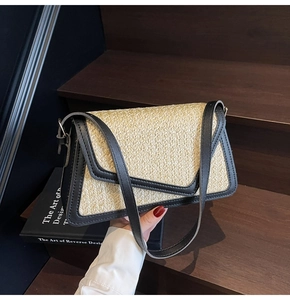 Detail of a straw crossbody bag with black leather trim on a wooden background