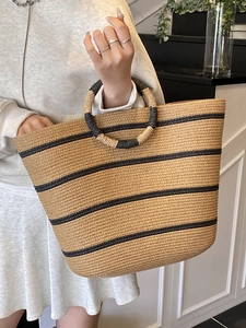 Summer straw woven tote bag with black stripes and circular top handles for beach vacations