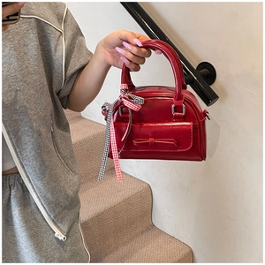 Détail d'un sac à main rouge en cuir verni avec nœud et ruban décoratif élégant