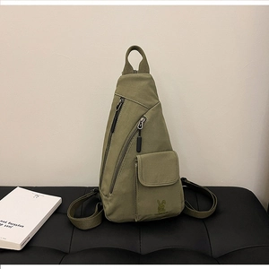 Detail view of army green canvas chest bag with multiple pockets and rabbit embroidery