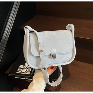 Detail shot of light blue textured shoulder bag with silver buckle on a wooden step