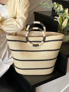 Large woven straw beach tote bag with black stripes and circular top handles for summer