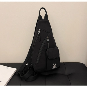 Detail view of black nylon chest bag featuring adjustable strap and embroidery