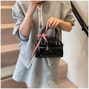 Sac polochon en cuir verni noir brillant avec détail de nœud à carreaux rouges
