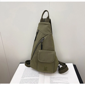 Close-up of military green canvas chest bag featuring a rabbit print on an open book