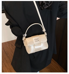 Detail view of woven leather mini bag with pearl handle and metal lettering on a model
