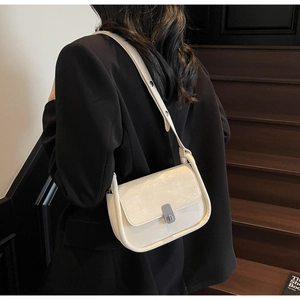 Detail view of cream white leather crossbody bag featuring an elegant silver metal buckle