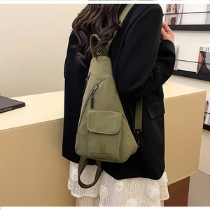 Close-up of military green canvas chest bag with multiple zippers on a female model