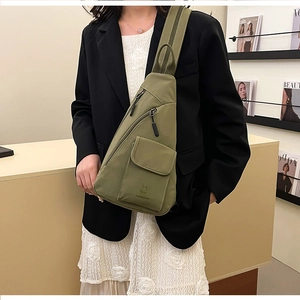Detailed view of an olive green nylon sling bag with multi-pocket storage for casual wear