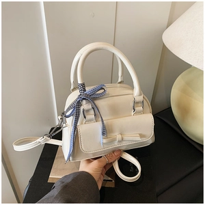 Détail du sac à main en cuir blanc crème avec poche à nœud et foulard à carreaux