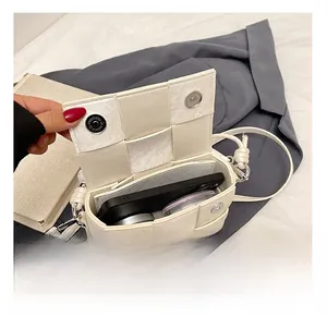 Detail shot of woven white leather crossbody bag interior showing phone storage space