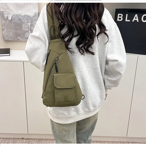 Detail of army green nylon crossbody chest bag with cartoon rabbit logo and flap pocket