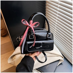 Détail du mini sac noir brillant avec ruban à carreaux rouges et poche à nœud chic