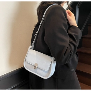 Close-up of a stylish grey crossbody bag with a silver metal clasp and matte finish