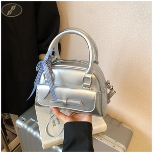 Détail d'un sac polochon argenté avec nœud et ruban à carreaux bleus pour un look chic