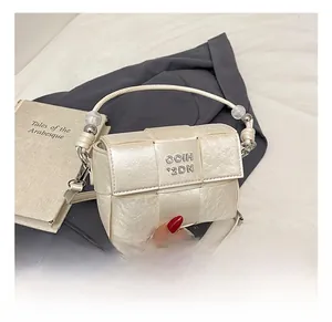 Close-up of cream woven handbag featuring pearl handle and metallic logo detail