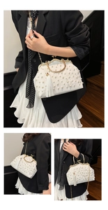 Close-up of white vintage handbag with pearl embroidery, floral patterns, and long silk tassel