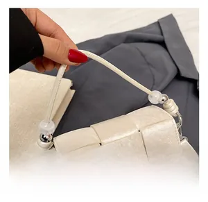 Detail of woven texture handbag with unique beaded handle and metallic logo plaque