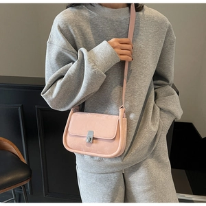 Detailed view of a pink matte leather square crossbody bag with silver twist lock on a model