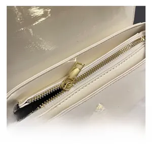 Close-up of white patent leather handbag featuring premium light gold zipper and hardware