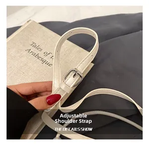 Detail of white leather shoulder strap with silver buckle and adjustable holes