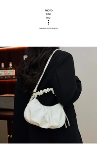 Close-up of cream crescent bag with pleated details and faux crocodile texture