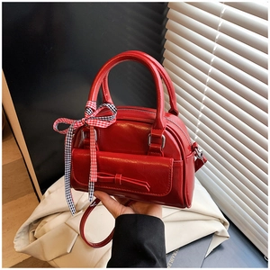 Détail du sac à main rouge en forme de coquillage avec noeud et ruban à carreaux
