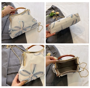 Detail of vintage floral embroidery on white handbag with golden metal frame clasp