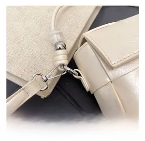 Detailed close-up of premium silver metal hook with decorative bead on cream woven bag