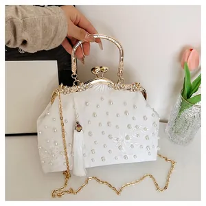 Close-up of white satin evening bag with floral embroidery and pearl embellishments