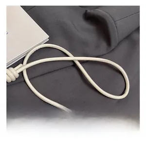 Detail of minimalist cream leather handbag featuring slender round straps and a knot detail