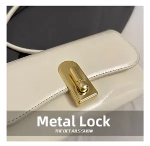 Close-up of the elegant golden metal clasp on a beige glossy leather handbag