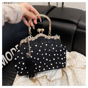 Detail of black lace evening bag with pearl embroidery, gold handle and silk tassel