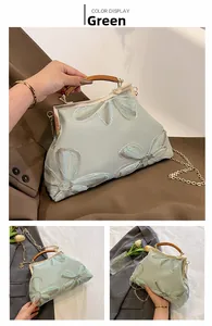 Detail of green floral crossbody bag with wooden handle and gold chain strap