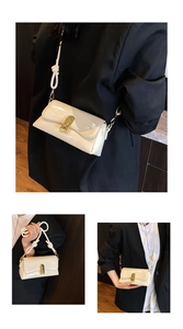 Detail of cream patent leather crossbody bag with gold lock and knotted shoulder strap