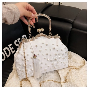 Detail of luxury pearl evening bag with floral embroidery and golden tassel charm