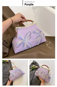 Detail of purple floral embroidered handbag with vintage gold metal clasp and wood handle