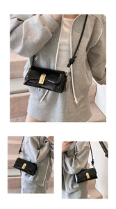Detail of a black patent leather crossbody bag with gold buckle and knotted strap