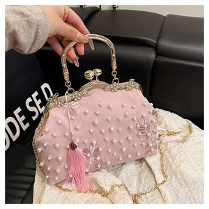 Close-up of pink satin evening bag with white pearl embroidery and luxury gold metal hardware