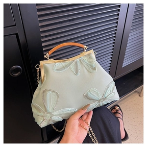 Detail of mint green embroidered clutch with 3D mesh flowers and vintage wooden handle