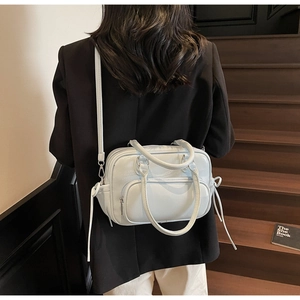 Litchi pattern light blue tote bag shown on model's back in a minimalist indoor setting