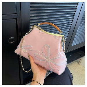 Close-up of pink satin handbag with floral embroidery and amber resin handle