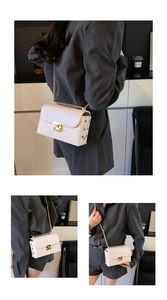 Detail of white mini crossbody bag with gold chain strap and side rivet decorations